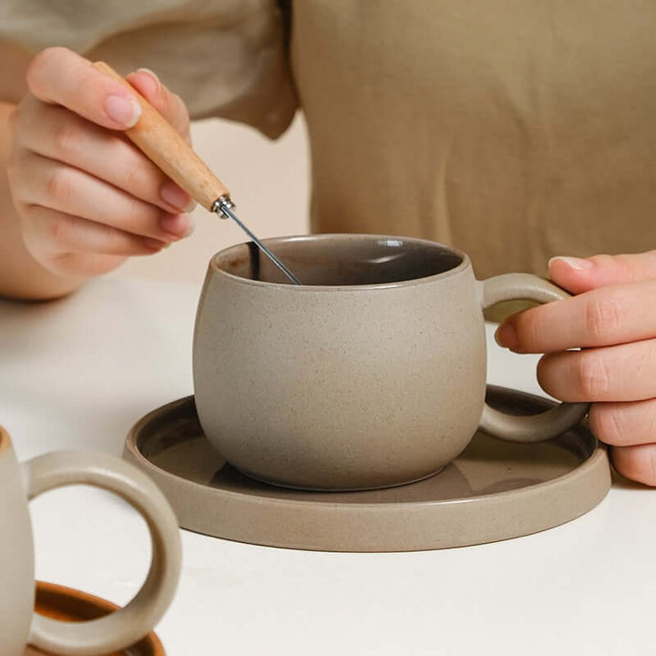 Person stirring coffee in ZenCrafter ceramic mug set with matching saucer inspired by traditional Japanese stoneware.